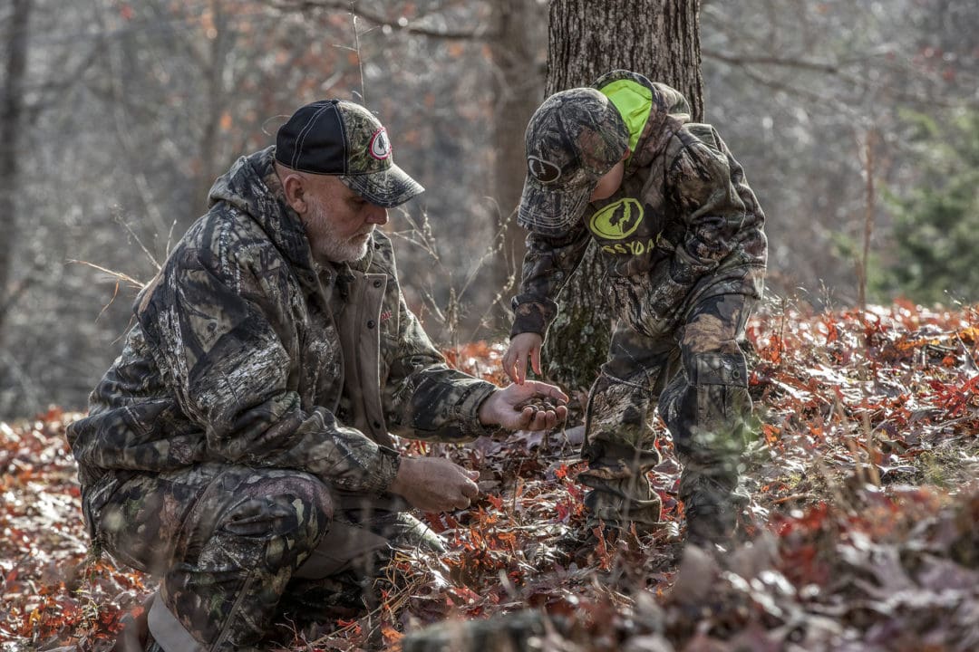 Grandfather teaching grandson about wildlife in Mossy Oak Brand Camo.